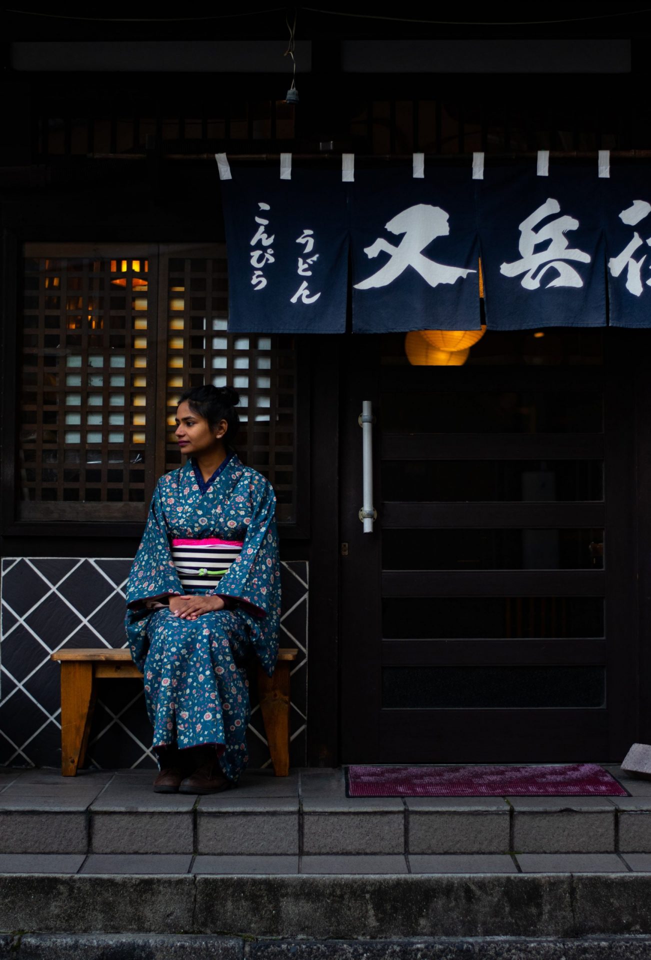 woman dressed in kimono waiting for her order infront of the restaurant