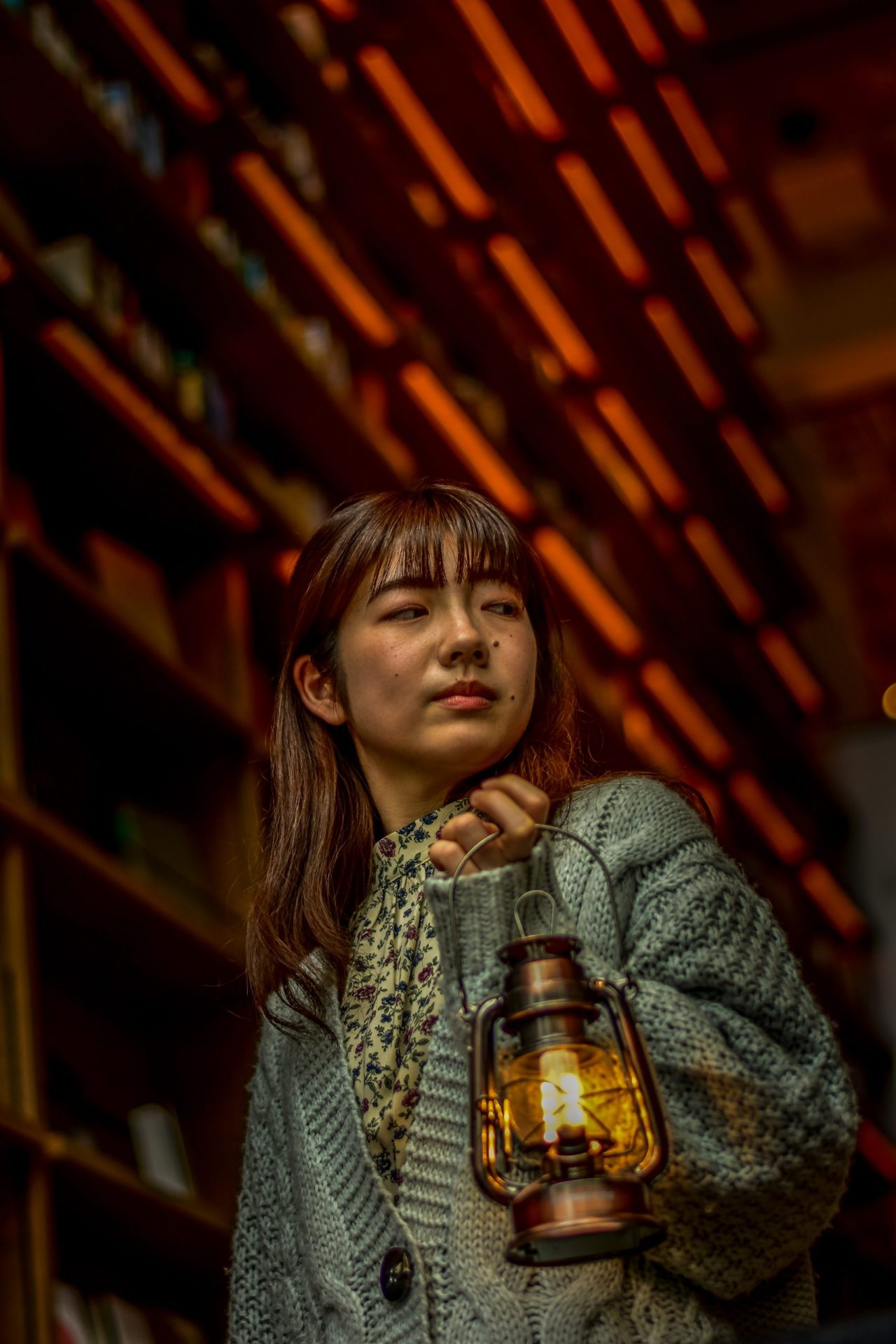 A japanese student girls portrait in a library with a lamp in her hand