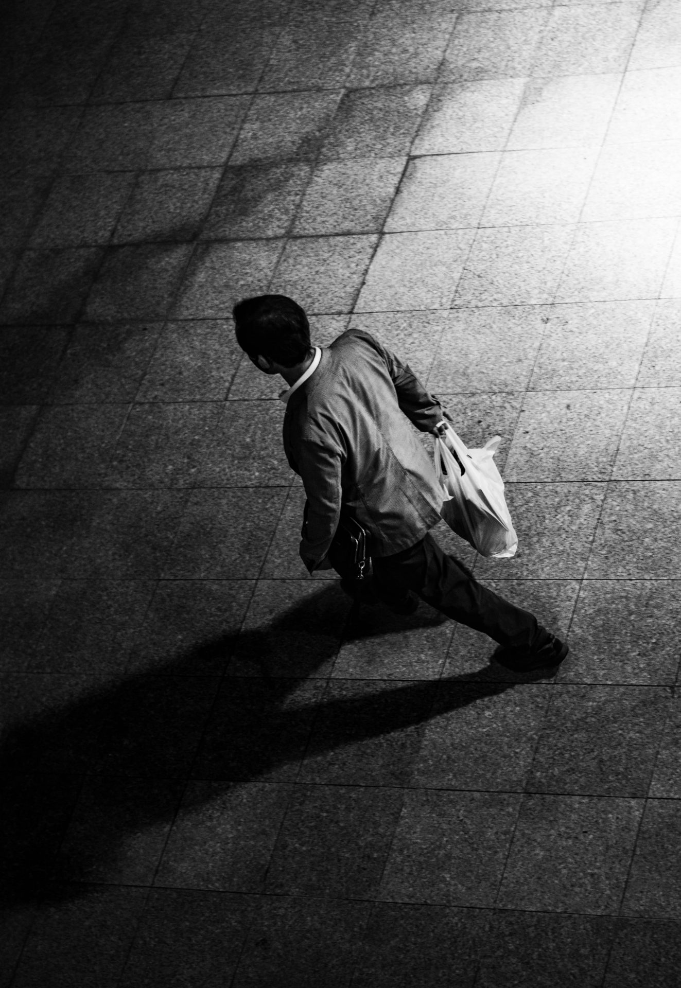 Minimalist black and white photography witha walking man and his shadow